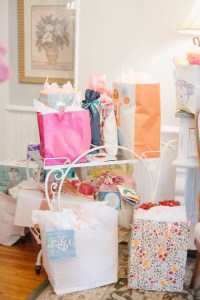 A collection of colorful gift bags and boxes are arranged on a decorative white shelf in a cozy room, creating a festive and joyful atmosphere.