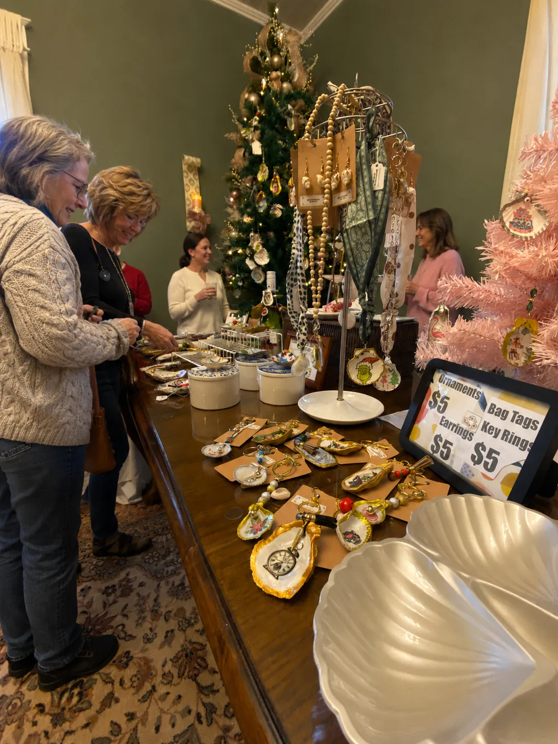 Holiday market display with handmade ornaments, jewelry, and decorated Christmas trees.