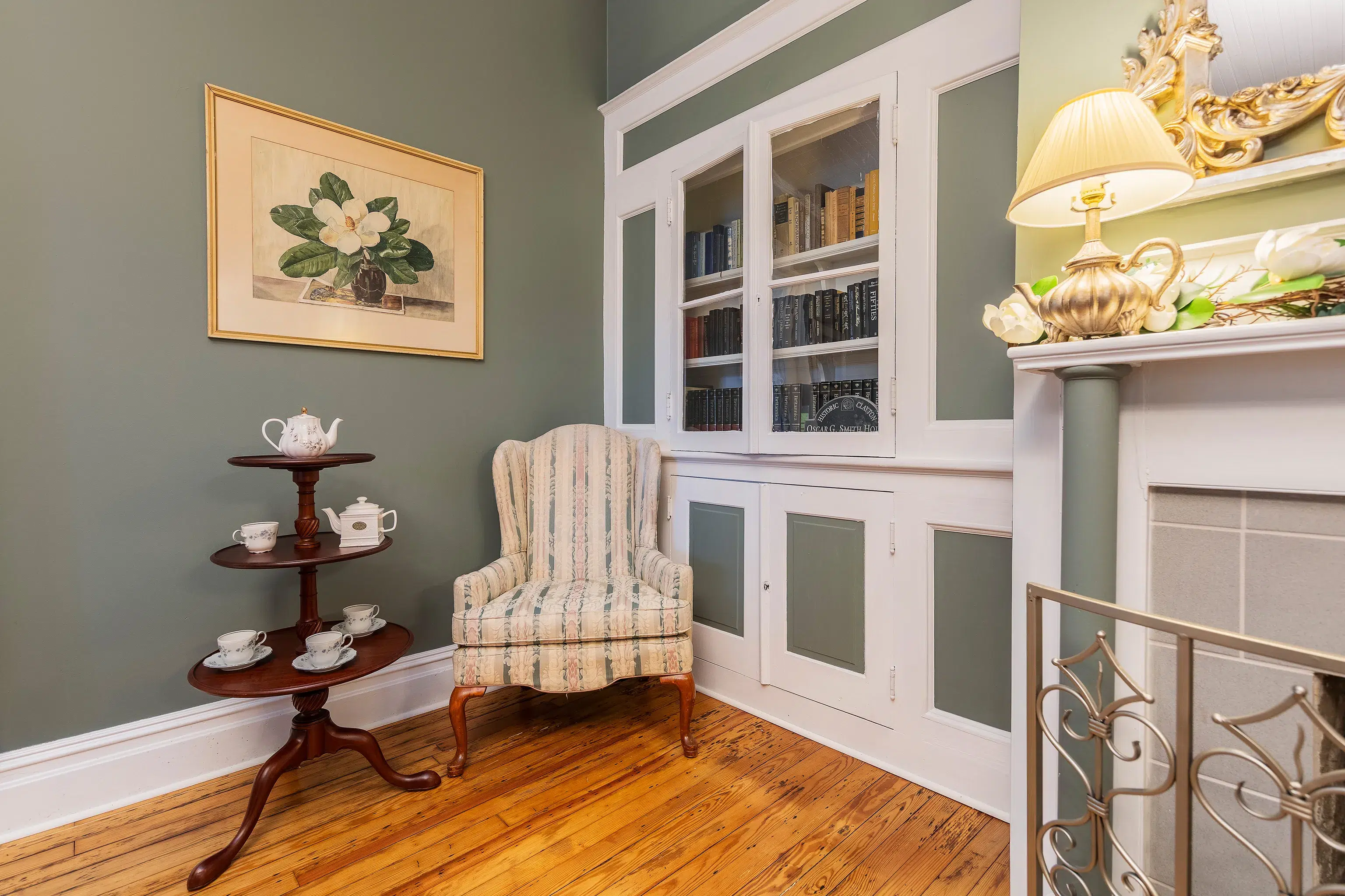 Cozy reading nook with a tea service, striped armchair, built-in bookcase, and fireplace.