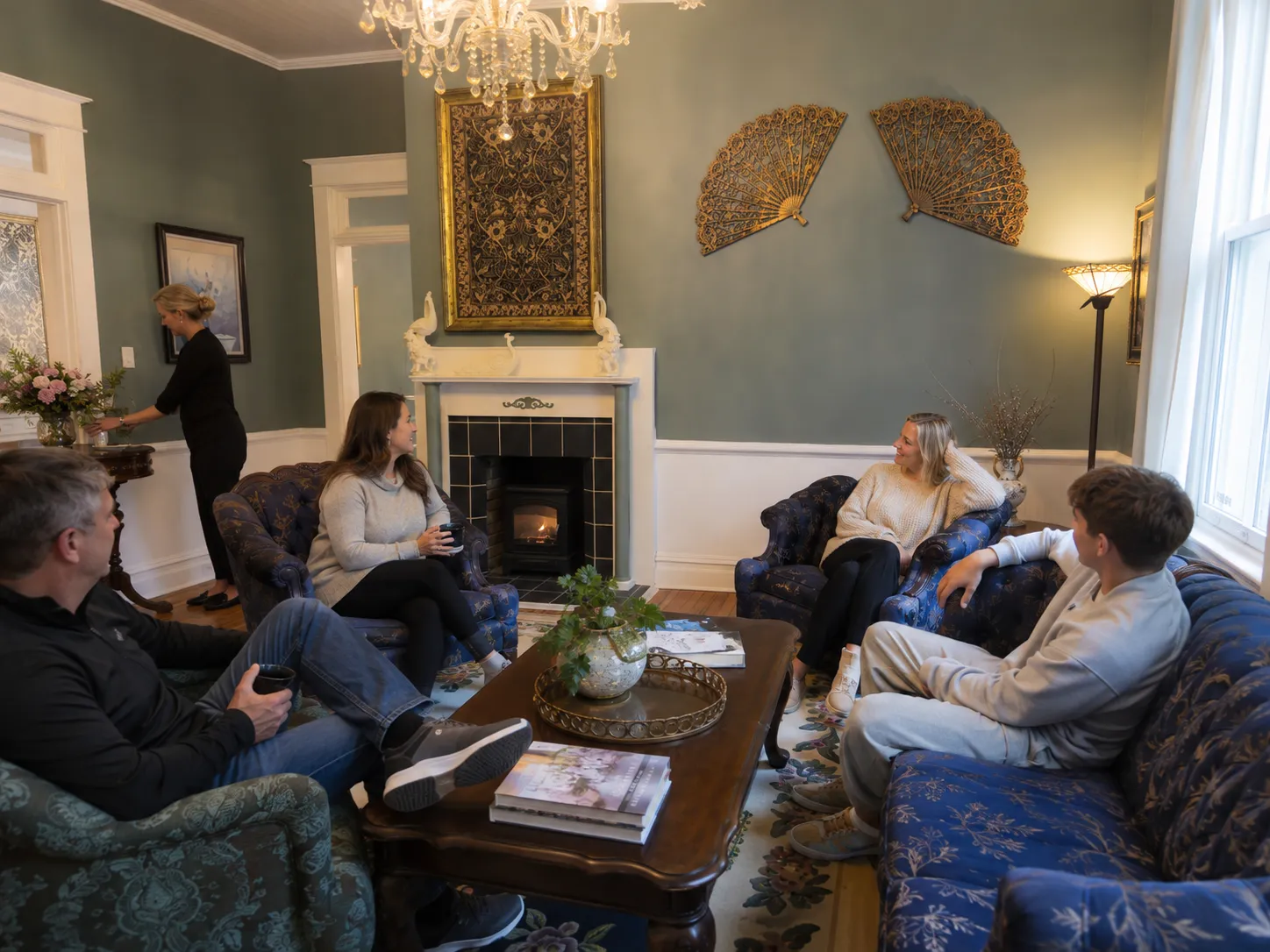 Guests relaxing by the fireplace as a host arranges flowers during an exclusive full-inn stay.