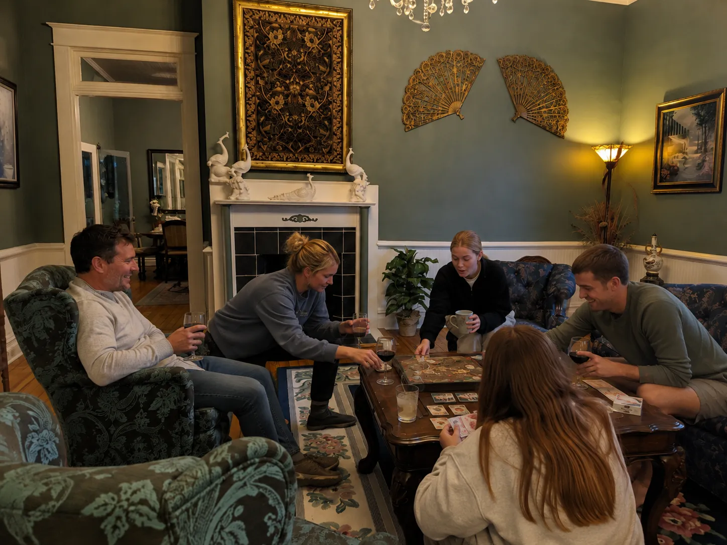 Friends playing cards and sharing drinks beside the fireplace during a private estate stay.